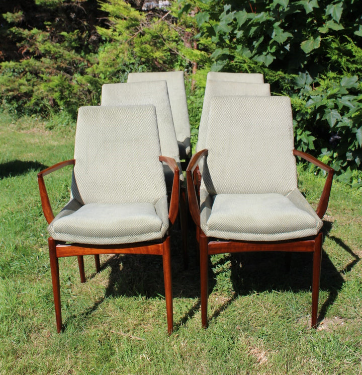 Detailed view of a mid-century modern dining chair with carved accents, rosewood finish, and enclosed upholstery