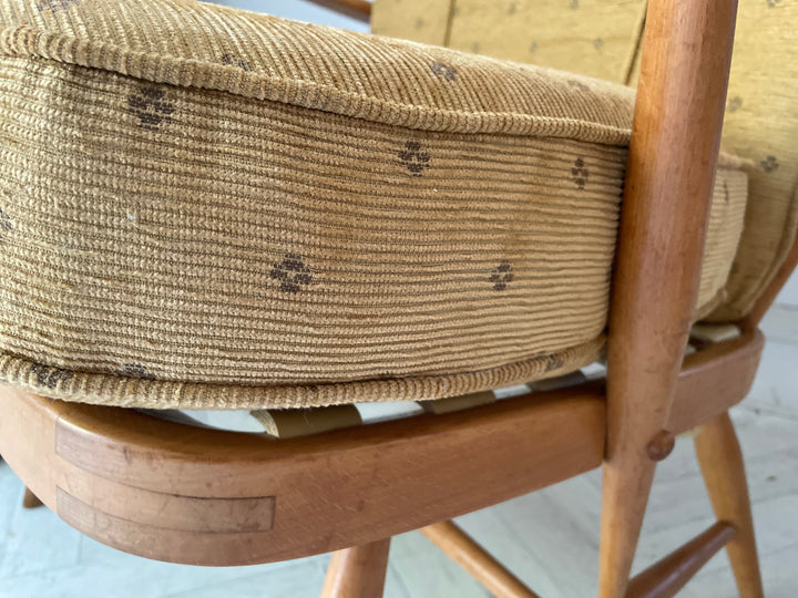Ercol high back lounge chairs Close-up of a wooden chair with a woven seat on a light-colored floor.