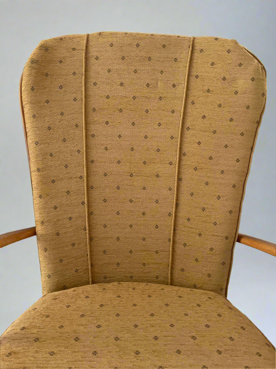 Mustard upholstered Ercol grandfather armchair with a subtle pattern on a white background