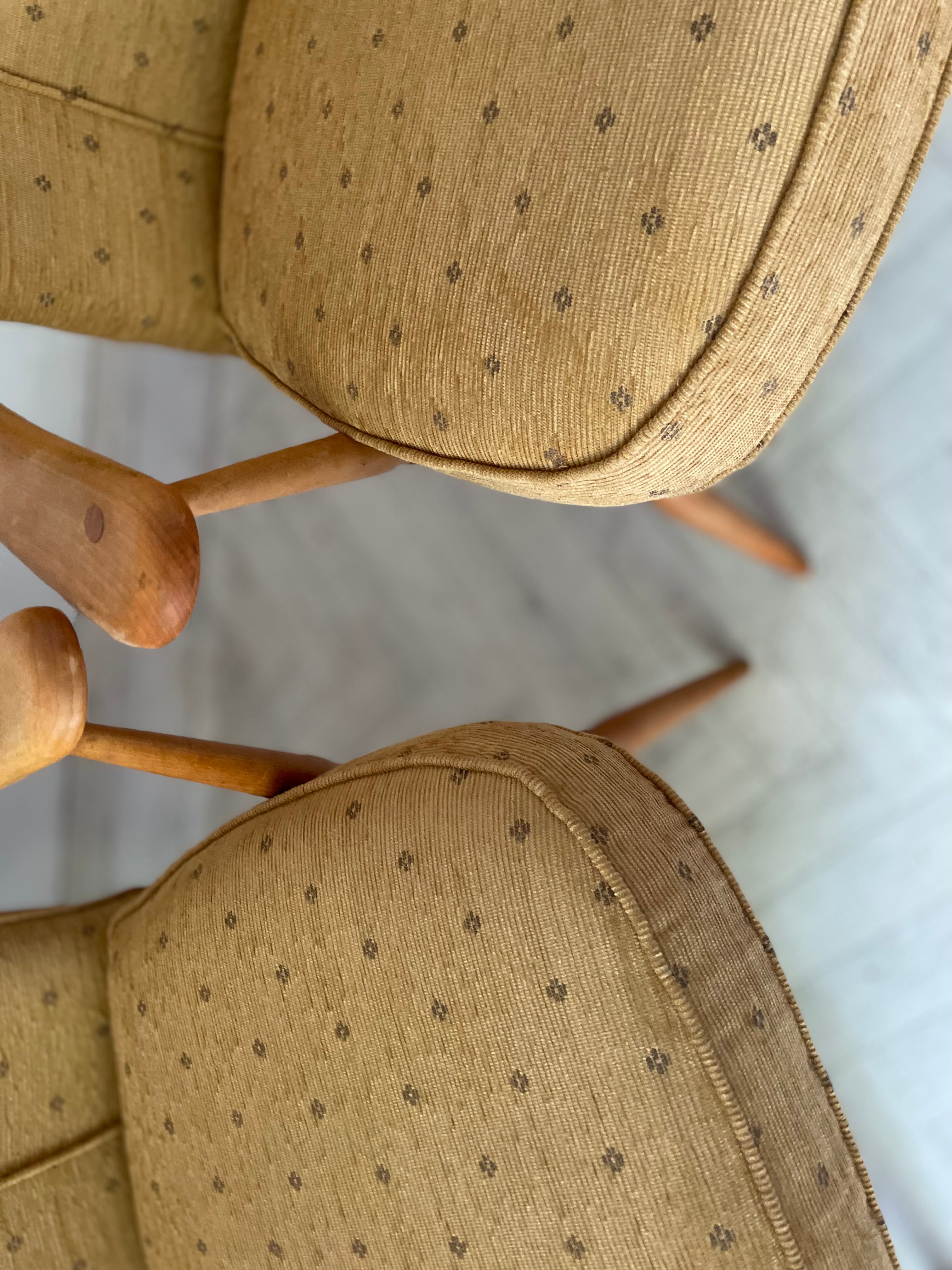 Close-up of a chair with patterned beige cushions on a light background