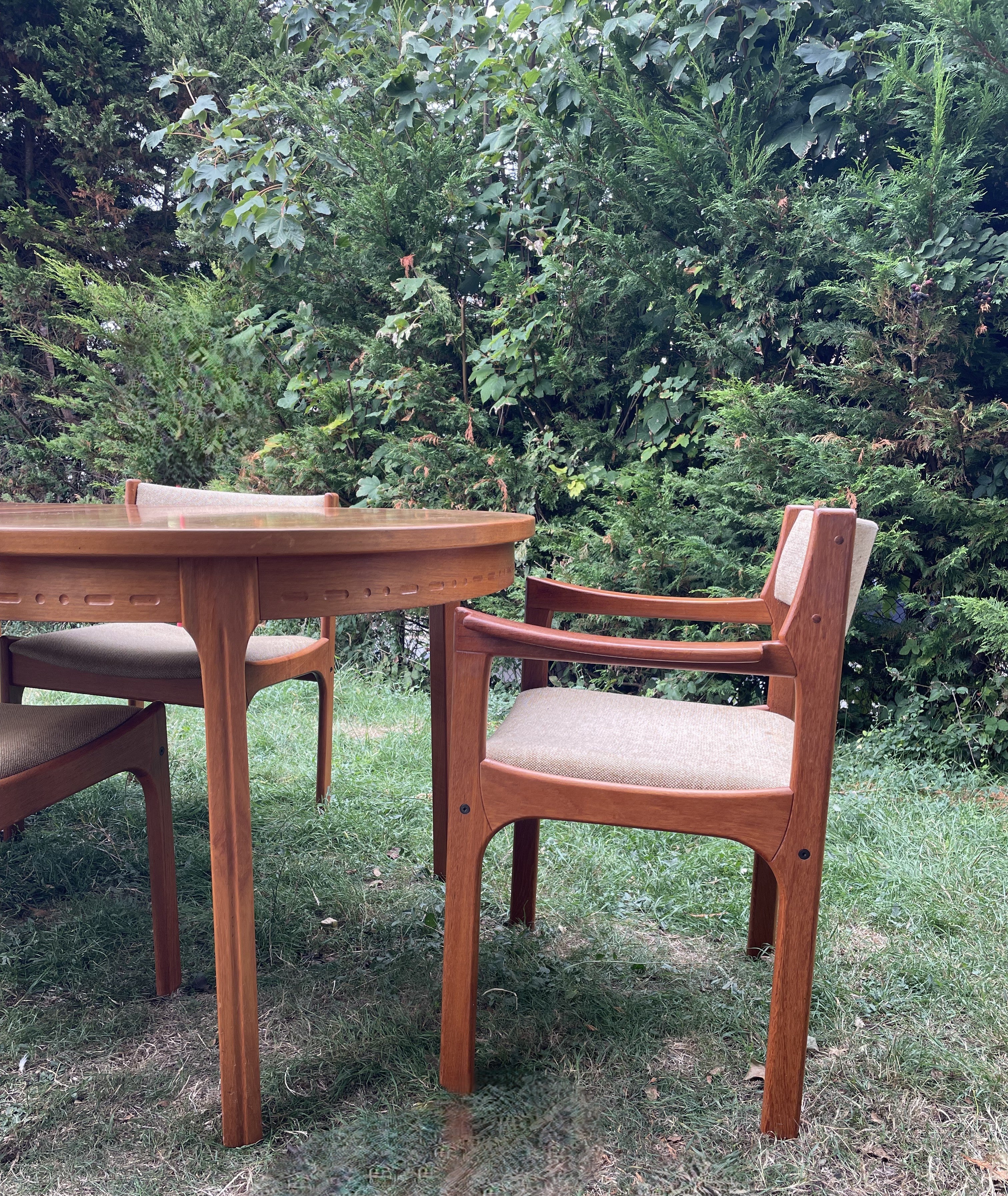 Wooden outdoor table and chairs with a green, leafy background