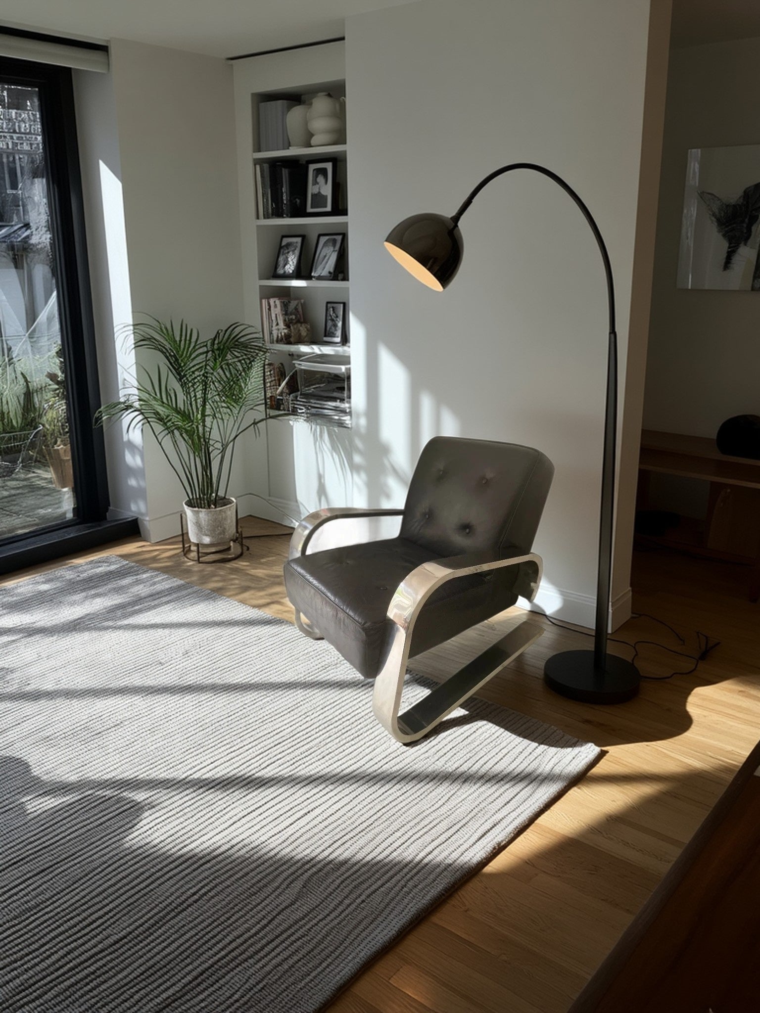 Modern living room with a gray armchair, floor lamp, and bookshelf.