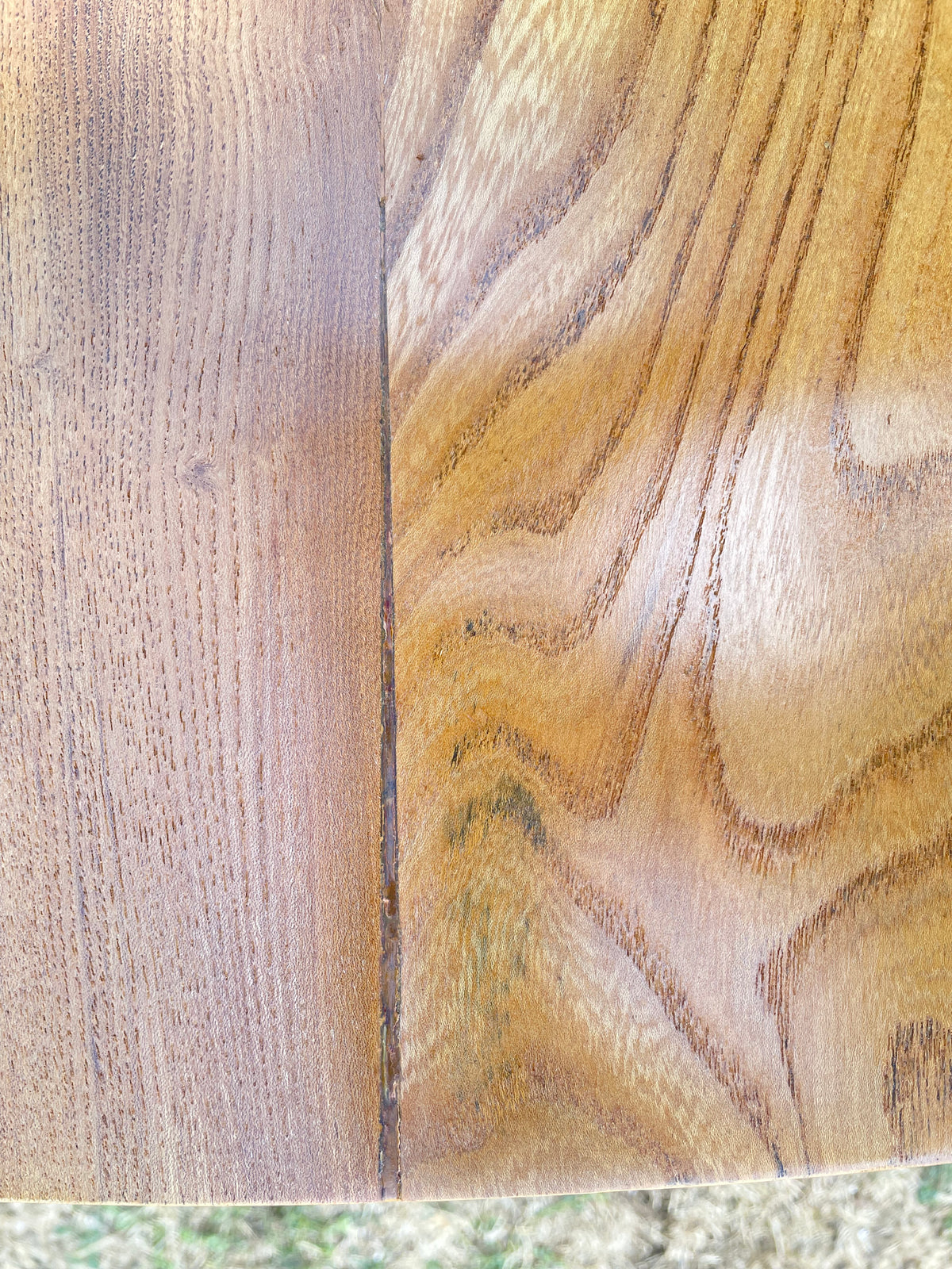 Close-up of a wooden surface showing two different wood finishes side by side, with a vertical seam down the middle