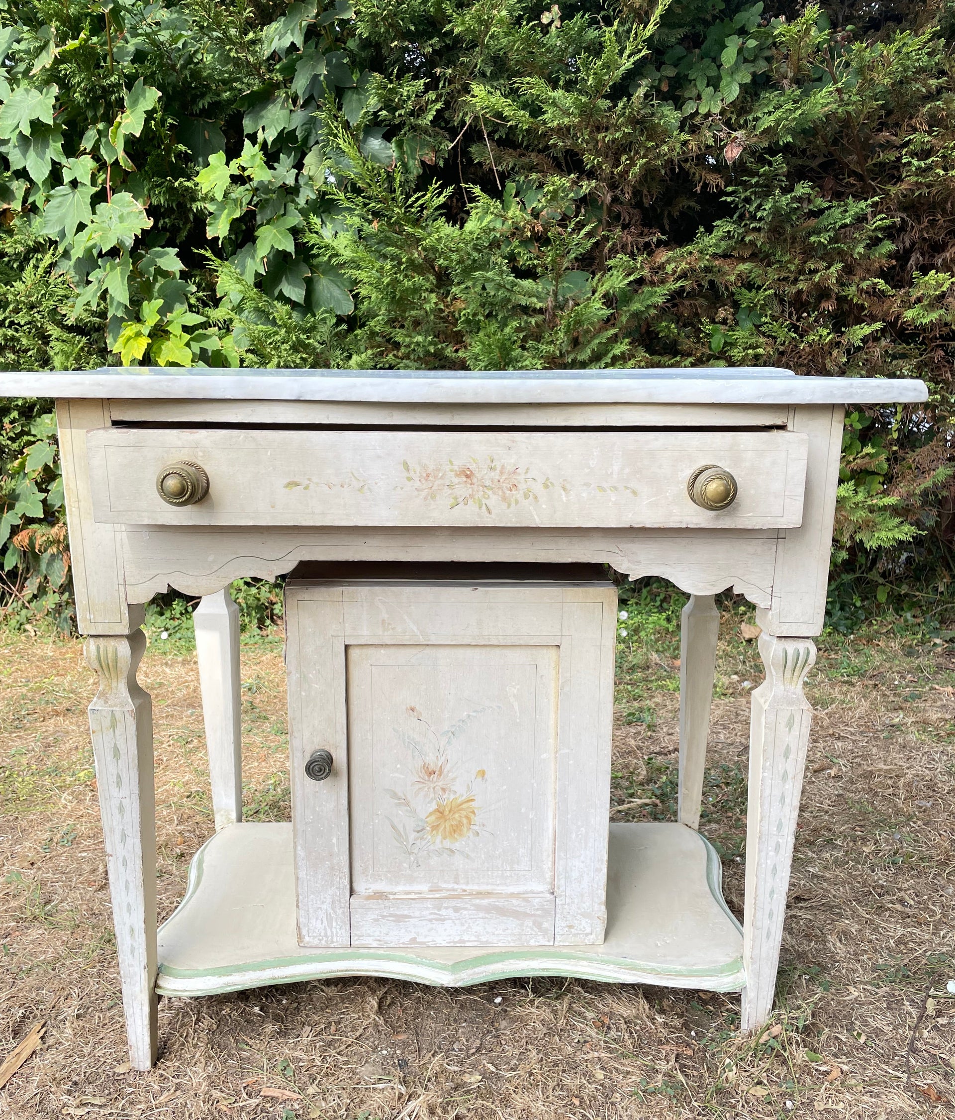 Suggestion


A distressed white painted wooden chest of drawers or console table with a single drawer, shown outdoors on grass next to green bushes.
