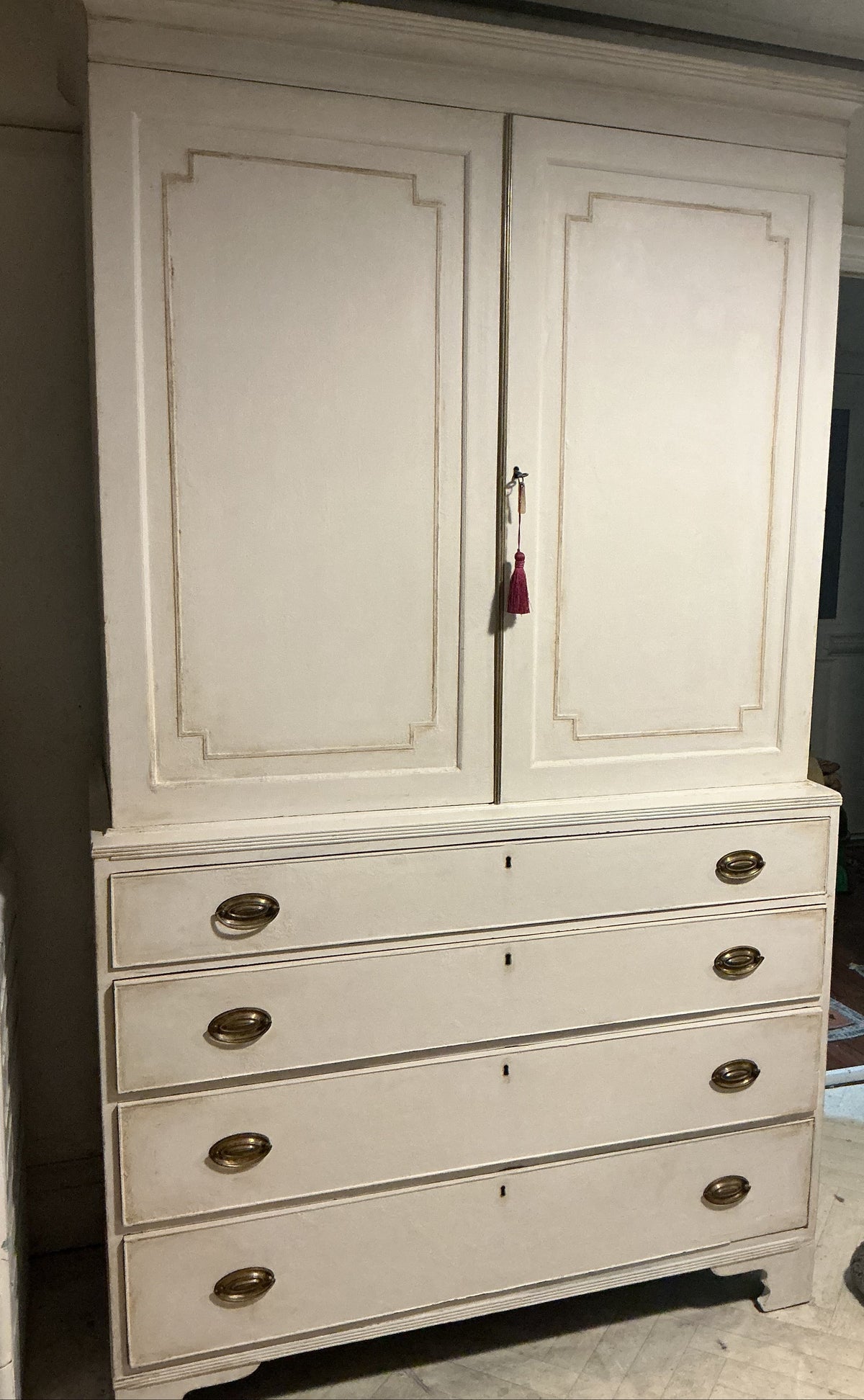 tall white painted wooden hutch or dresser with two upper cabinet doors and five drawers below, featuring distressed beige edging and brass oval handles