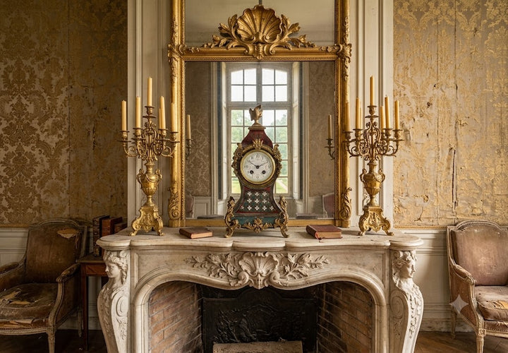 An ornate vintage room interior featuring a large gold-framed mirror above a carved white marble fireplace mantel. A decorative mantel clock sits centered in front of the mirror, flanked by two gold candelabras.