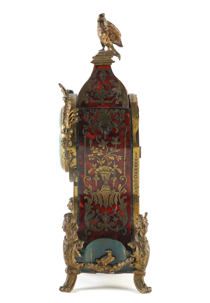 decorative antique-style clock with ornate gold-toned metalwork, red and gold floral detailing, and a bird perched on top, shown against a white background within a mobile app interface.