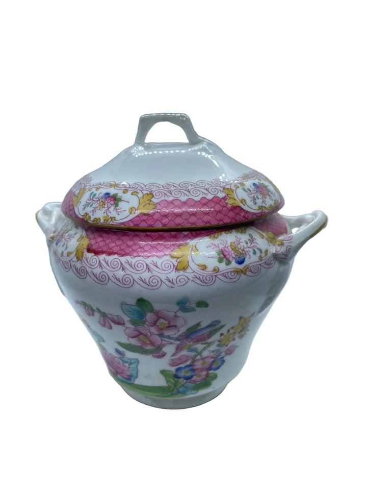 A white porcelain lidded sugar bowl or tureen with pink floral decoration and colorful painted motifs, photographed against a white background.