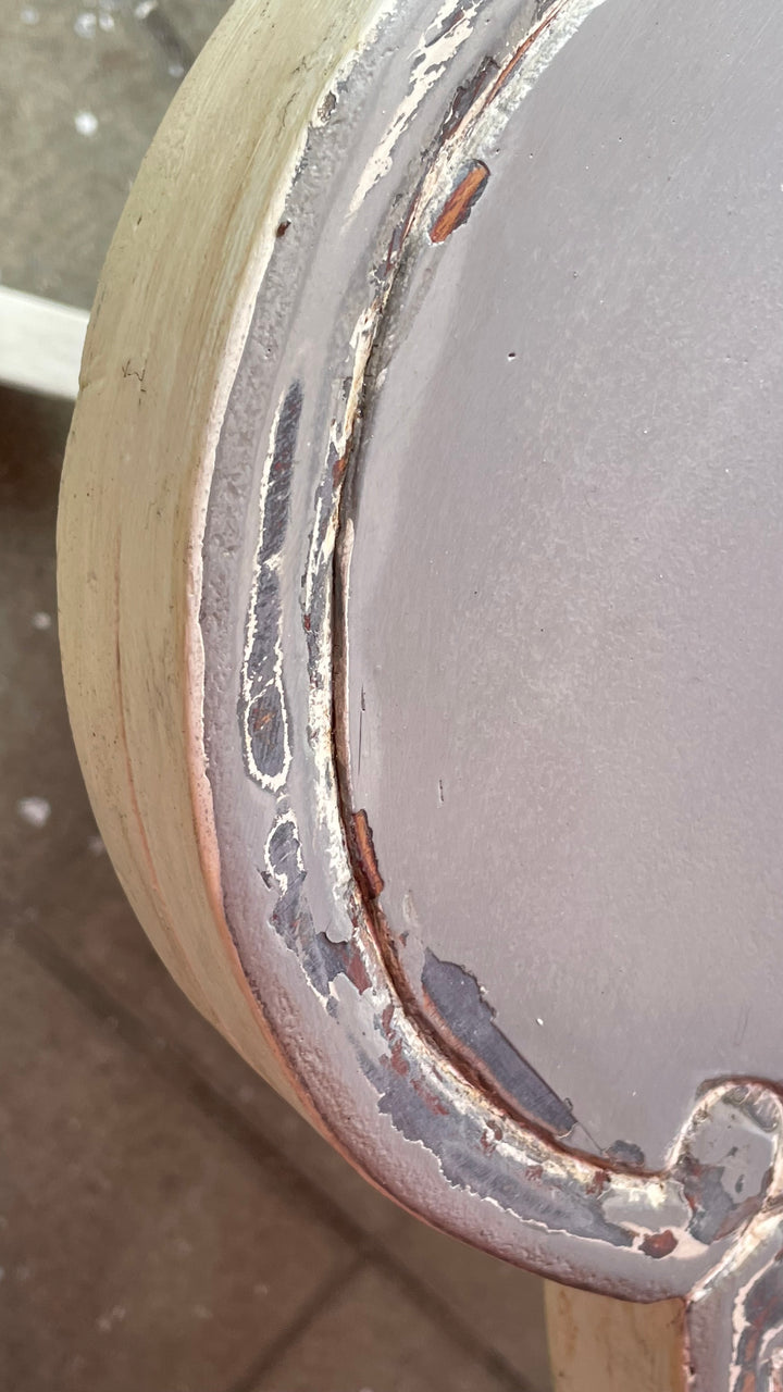 Close-up of a distressed metal circular component, showing a silver-gray surface with a heavily worn, rusted, and chipped copper-toned rim against a neutral background.