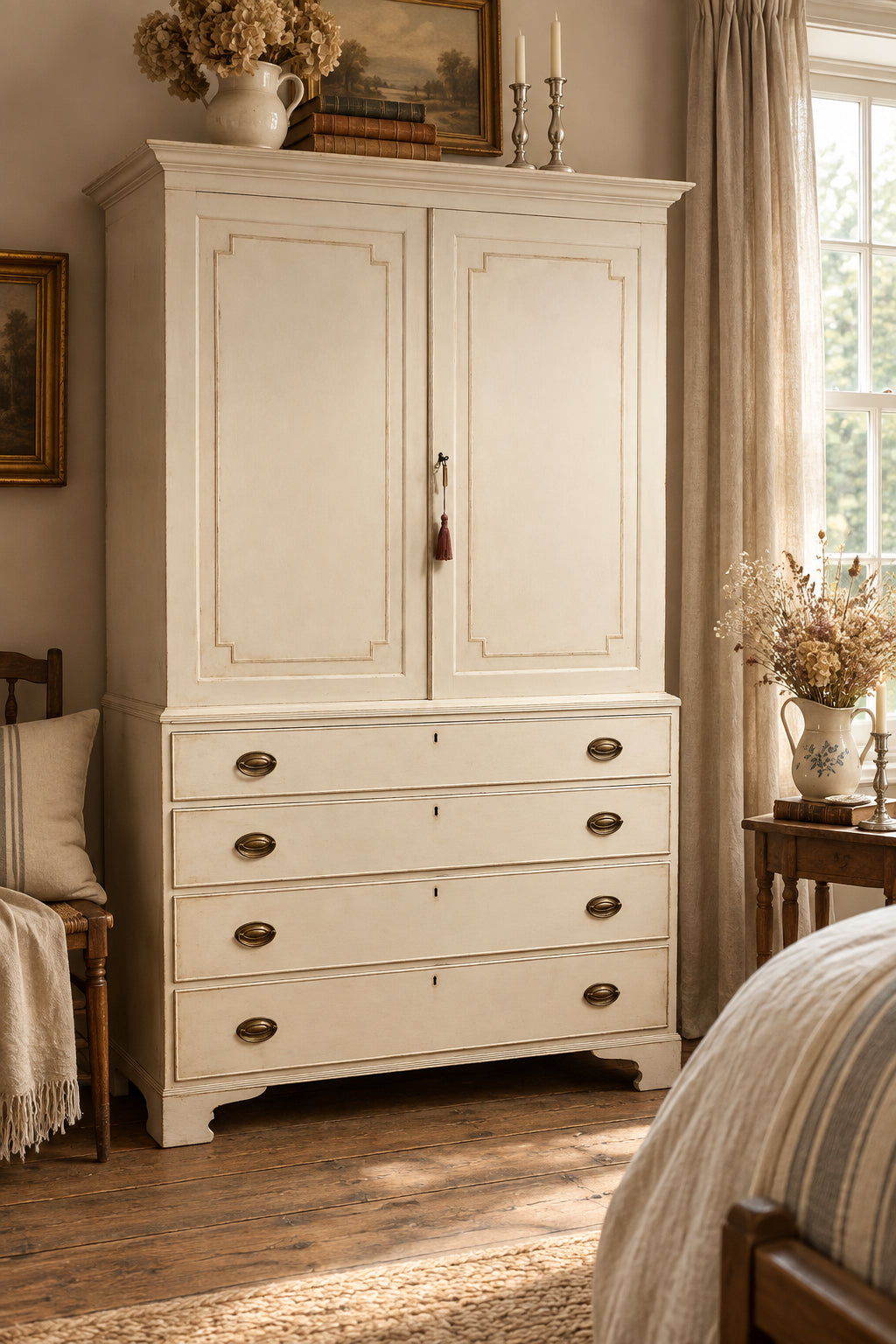 A tall, distressed off-white wooden cabinet with two upper doors and four lower drawers, featuring brass oval handles and a small hanging tassel, photographed in a home interior.