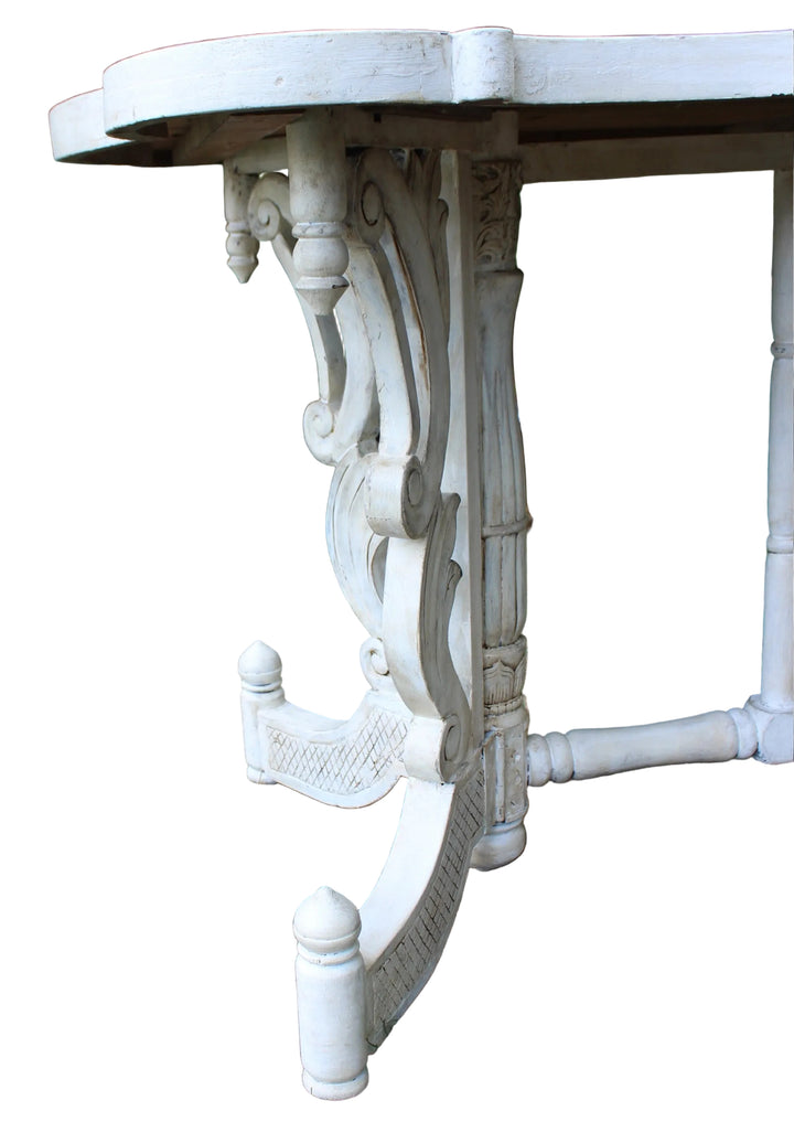 close-up outdoor shot of an ornate white carved table leg and part of the tabletop