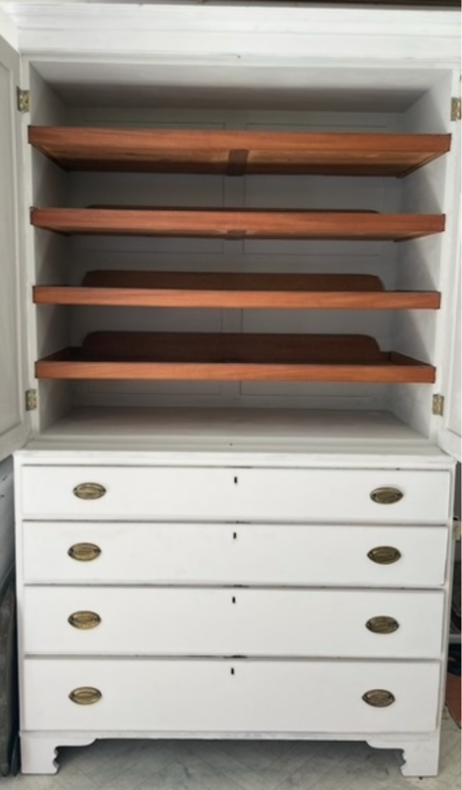 white wooden cabinet with five drawers and brass handles, featuring an open upper door with four wooden shelves inside, shown against a neutral indoor background.