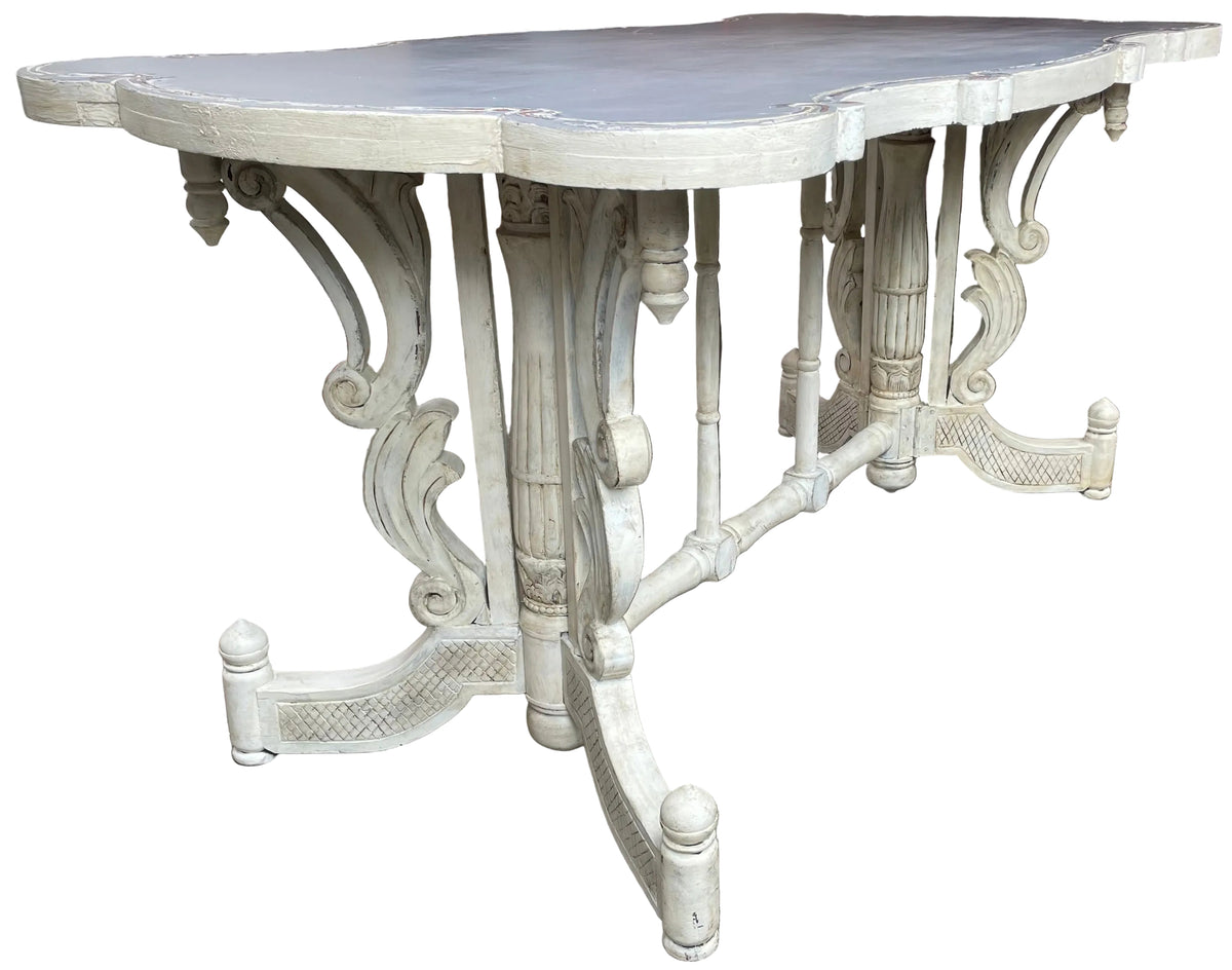 An ornate table with a distressed white painted finish.