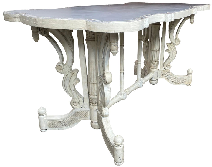 An ornate table with a distressed white painted finish.