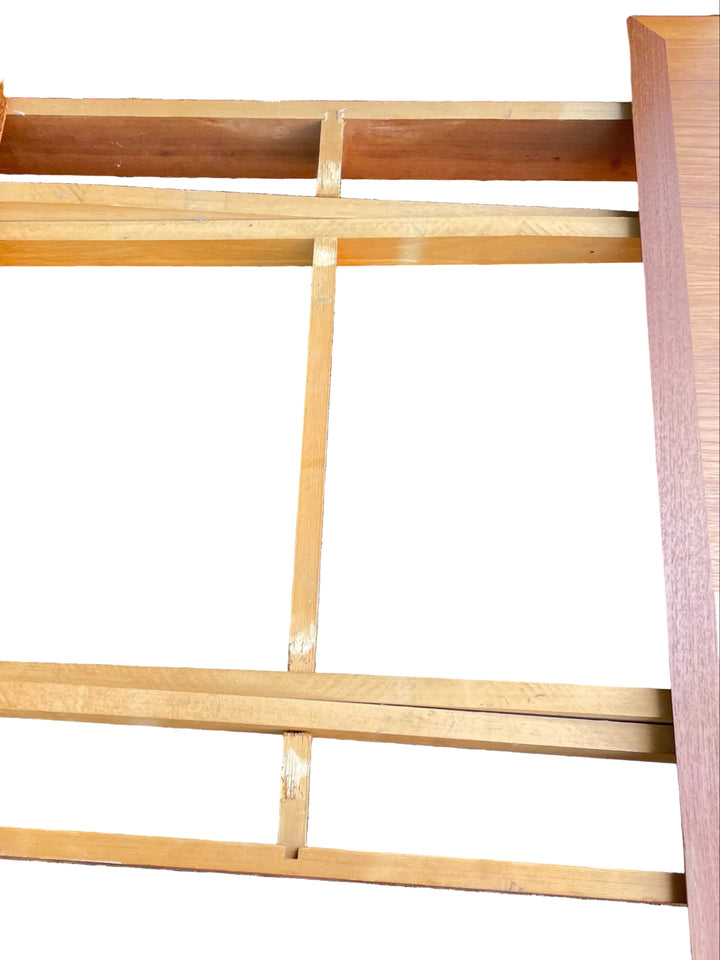 A close-up view of a wooden table frame or bench base made from natural oak and reddish-brown wood