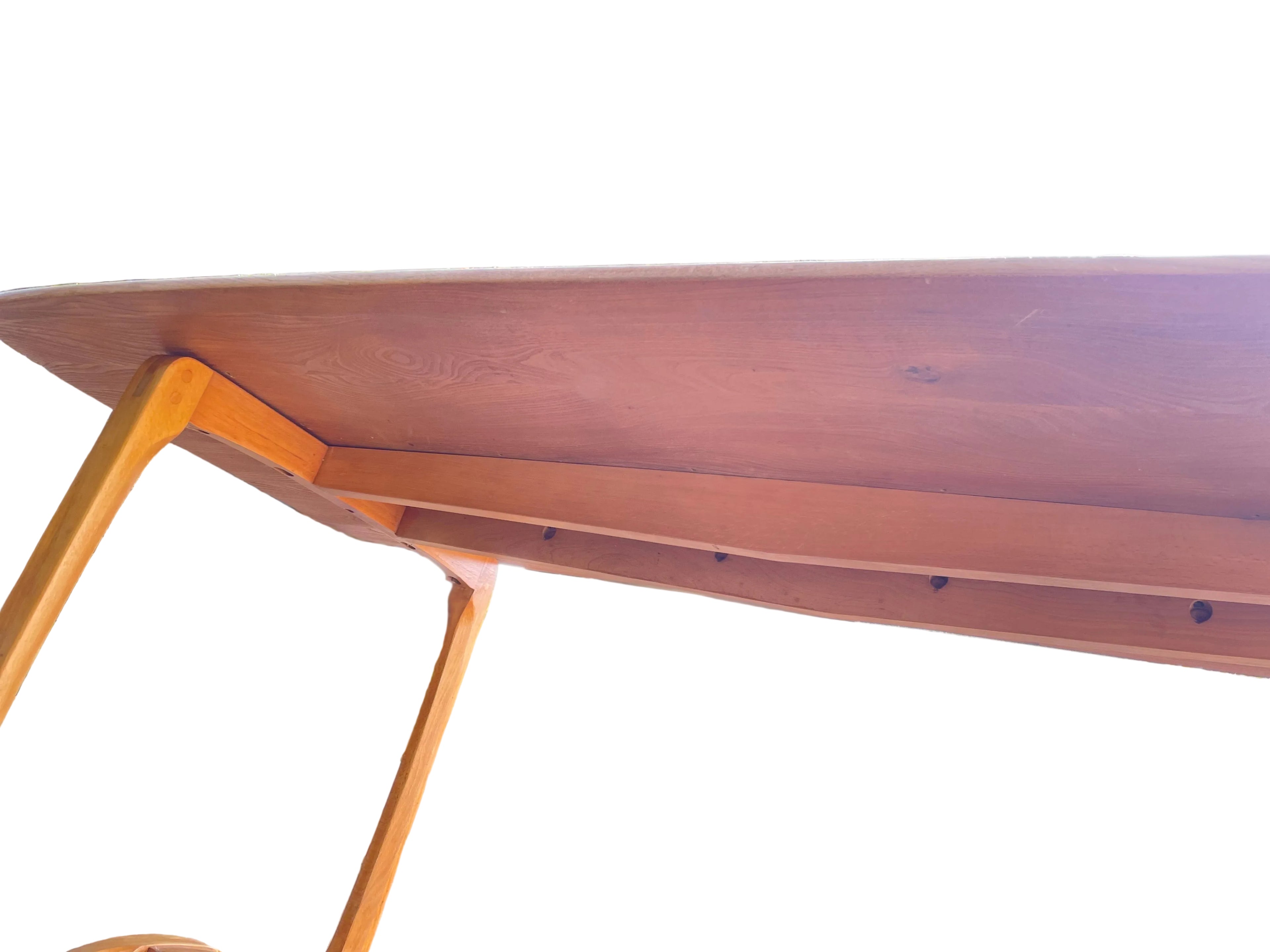 close-up, low-angle view of a wooden table's underside and leg, showing a warm medium-brown wood grain.