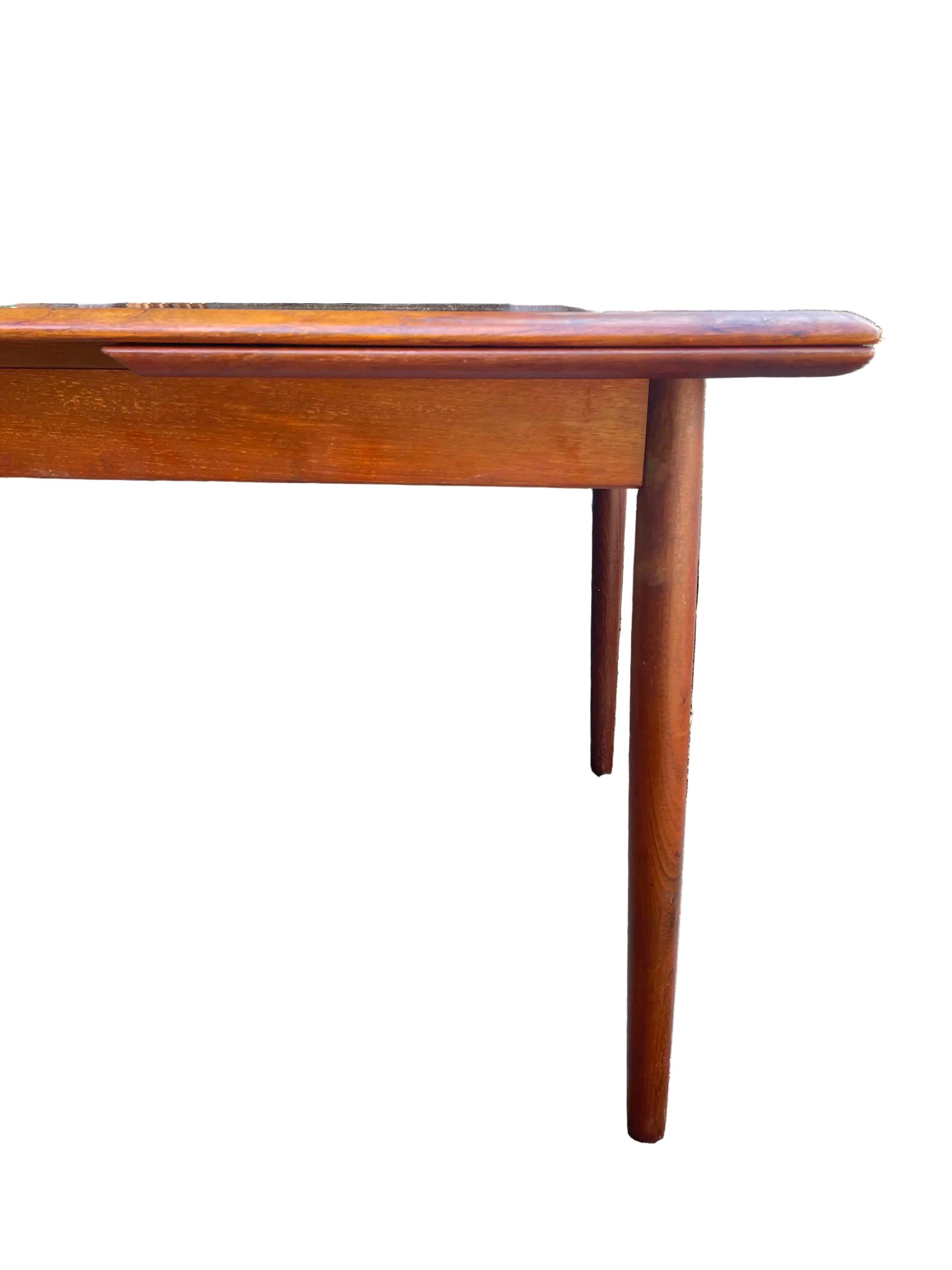 A mid-century modern wooden dining table with a warm reddish-brown finish End view
