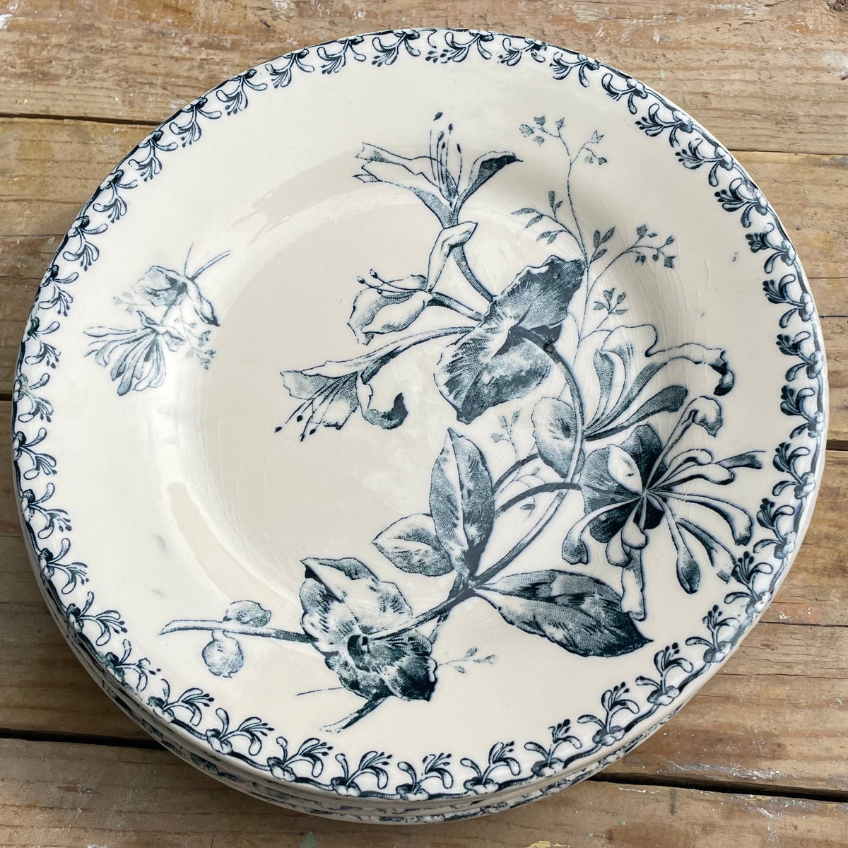 round ceramic plate with a blue floral and botanical print on a cream-colored background, resting on a rustic wooden surface.