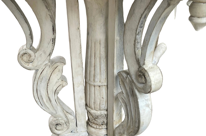 Close-up of ornate white carved outdoor furniture legs on a stone patio.