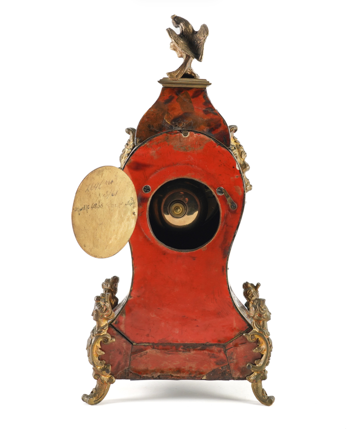 A red and gold antique-style mantel clock or decorative object shown on a white page within a phone screenshot, with black side panels and partial phone UI elements visible.