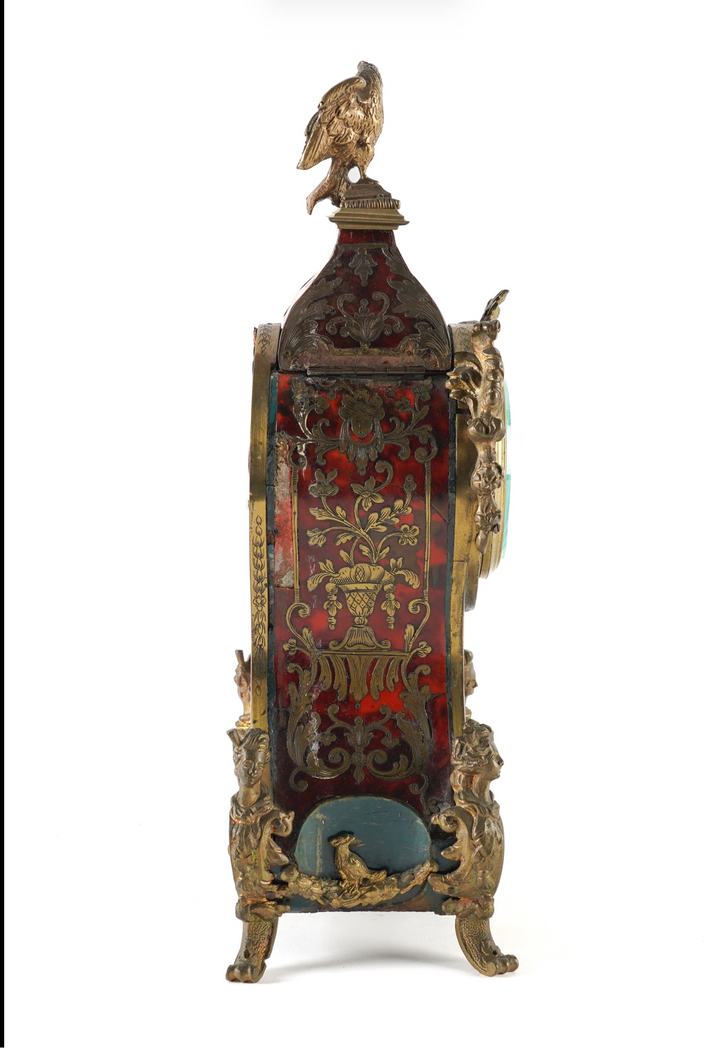 An ornate vintage-style decorative cabinet or display box with a gold-toned frame, intricate red and gold patterned front panel, a bird figurine on top, and a small blue cushion or panel near the base, shown on a white background within a phone app screenshot.