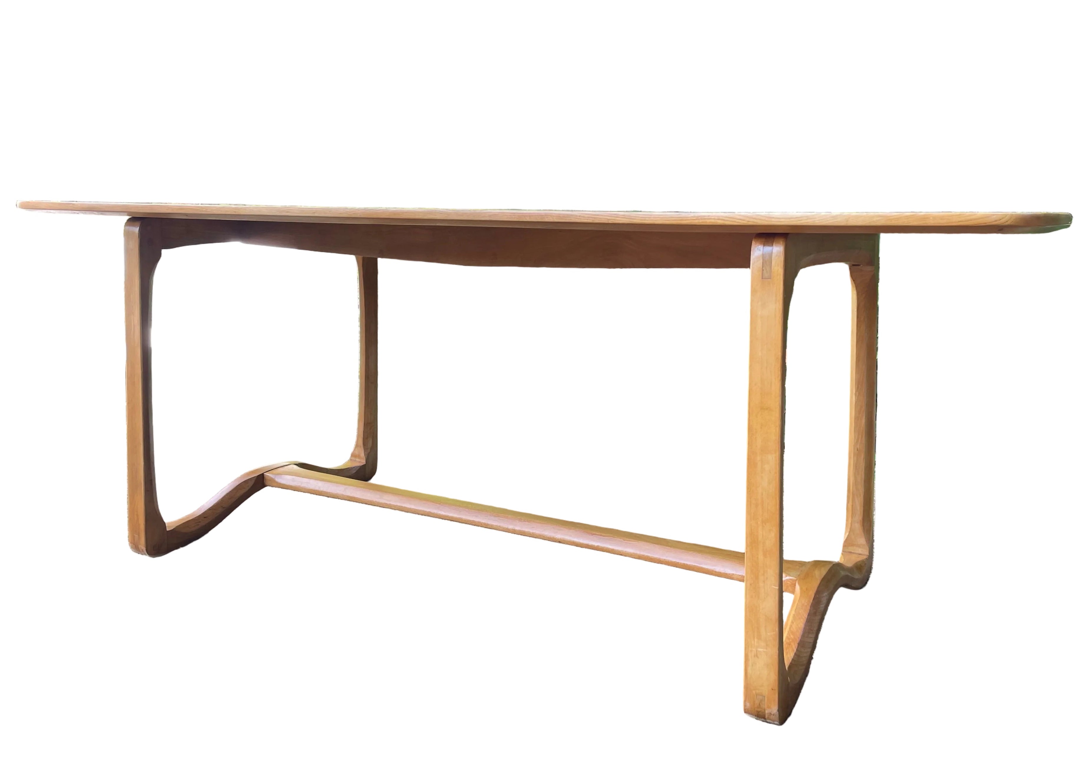 A mid-century modern Ercol wooden dining table with a warm medium-brown finish
