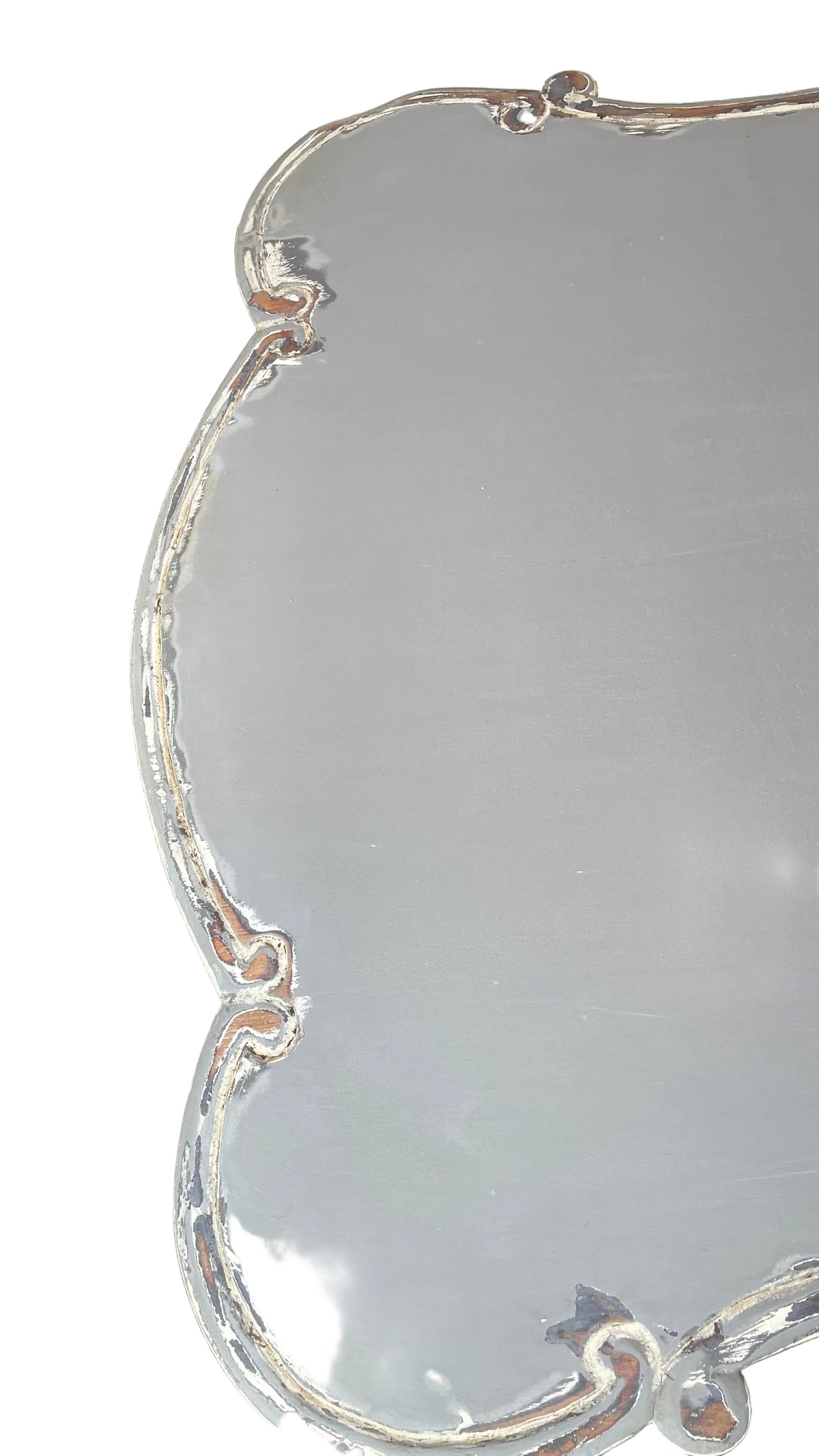 A large, scalloped-edge table or tray with a glossy silver finish, photographed outdoors on a concrete surface near a doorway.