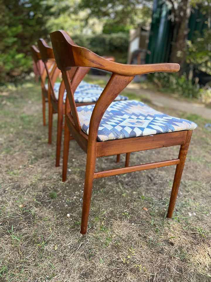 A mid-century modern wooden dining chair with a curved armrest and a blue and white geometric patterned cushion, photographed outdoors on a grassy lawn.
Details