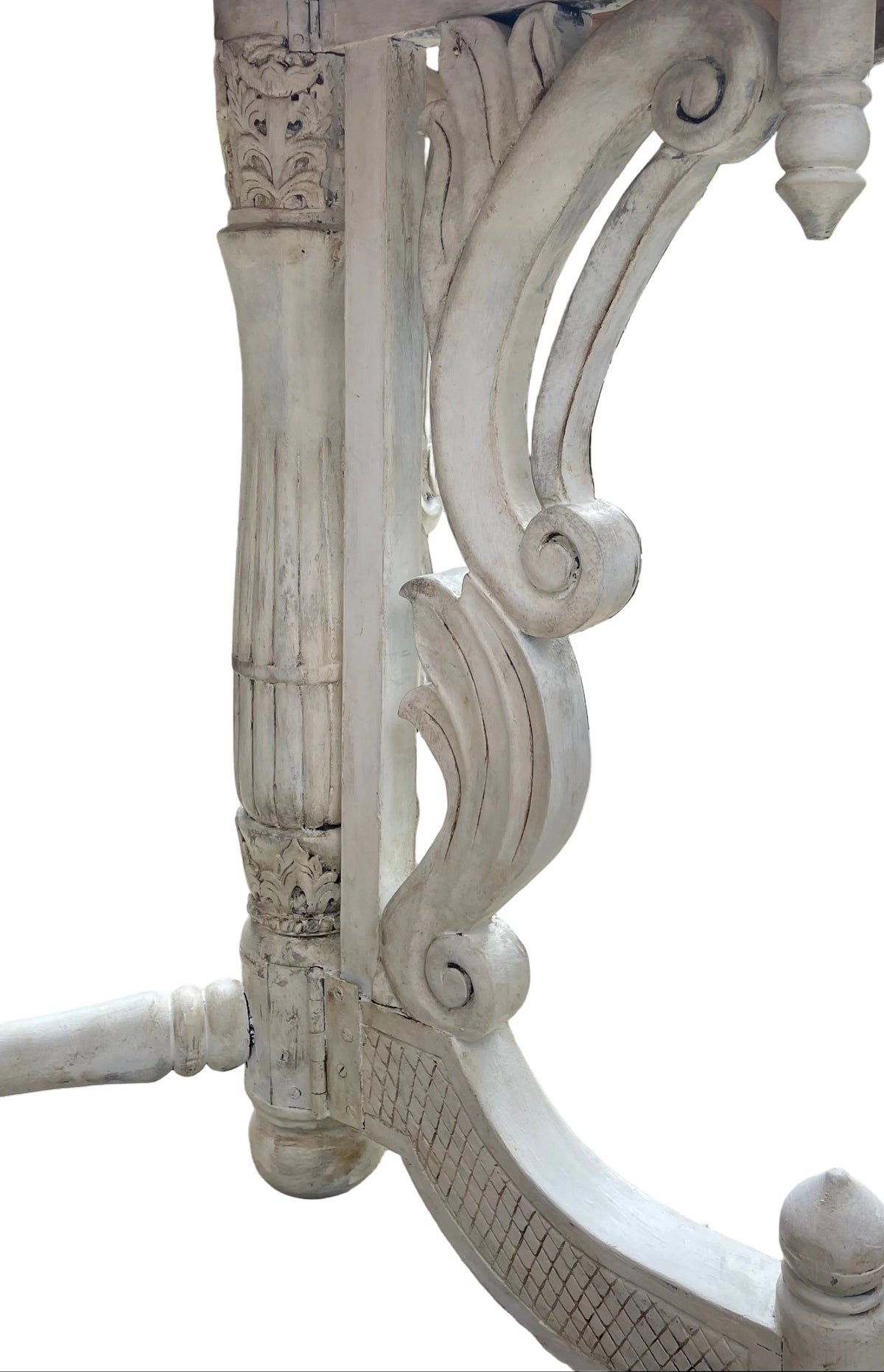 A close-up of an ornate white carved wooden table leg, showing distressed detailing and scrollwork