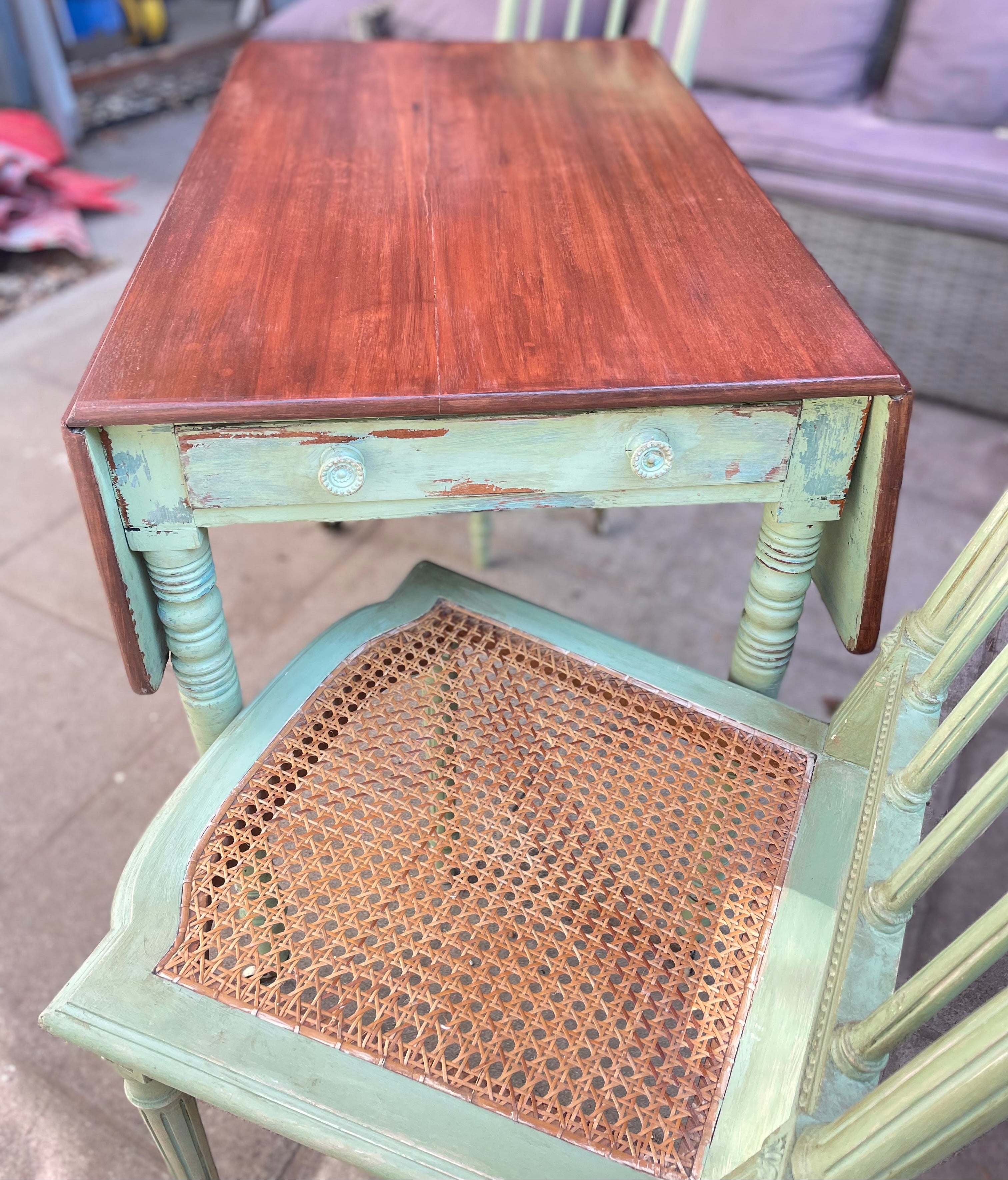 rustic distressed painted wooden table with a reddish-brown top and a peeling light green frame