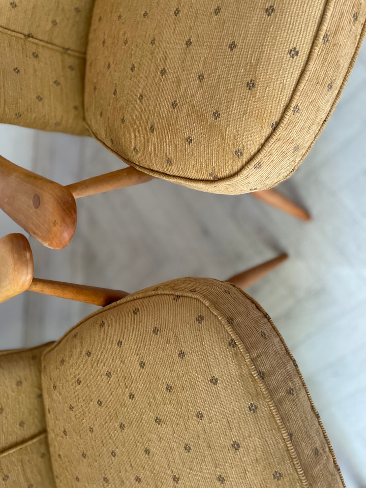 Close-up of a chair with patterned beige cushions on a light background