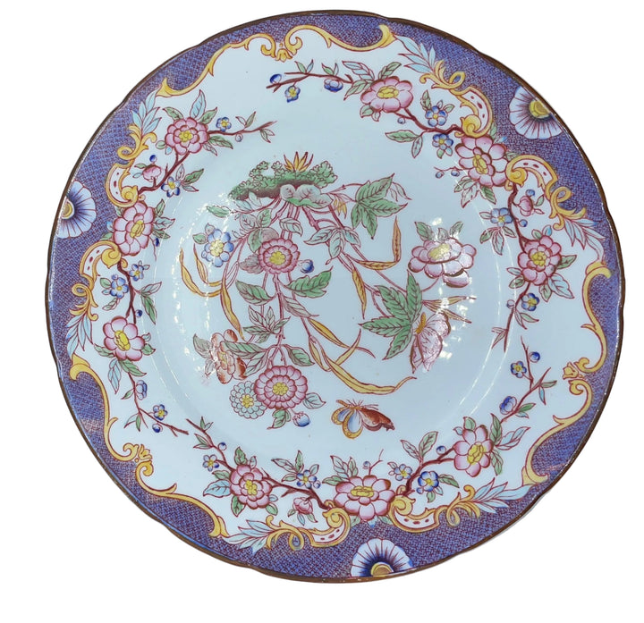 round white porcelain plate with an ornate floral pattern, featuring a purple border, yellow scrollwork, and pink flowers, shown inside a white box.