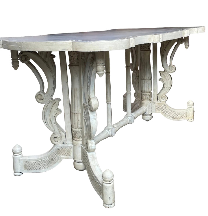 white carved outdoor dining table with ornate legs, photographed on a patio under a red canopy with a garden shed and patio furniture in the background.
Details