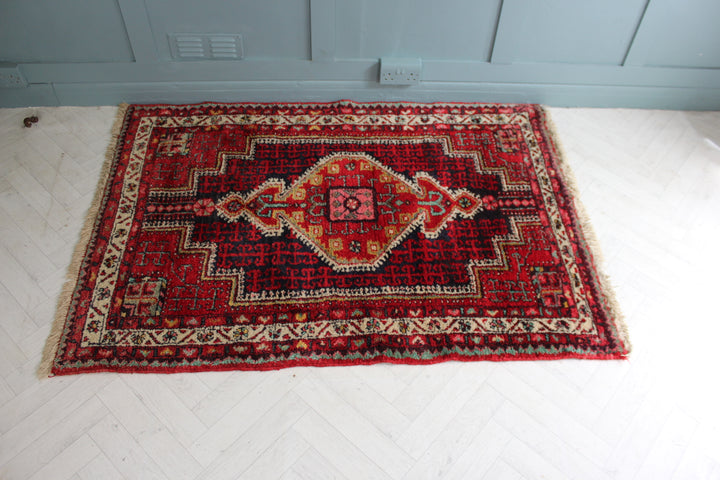 Vintage Persian rug with central diamond medallion design and white fringe, hand-knotted circa 1970s.