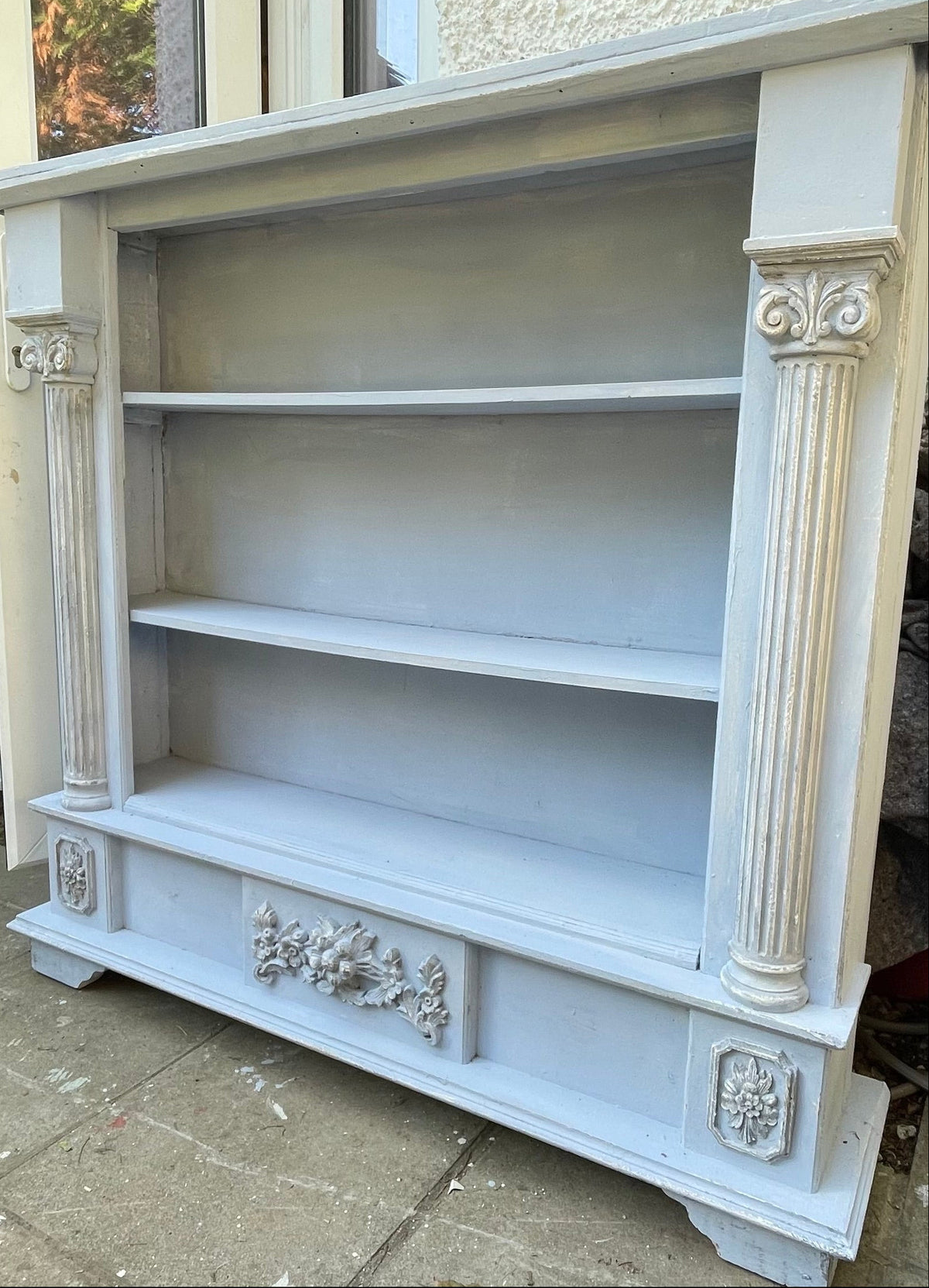 A large, antique-style painted bookcase with four shelves, decorative pillars, and carved detaiL