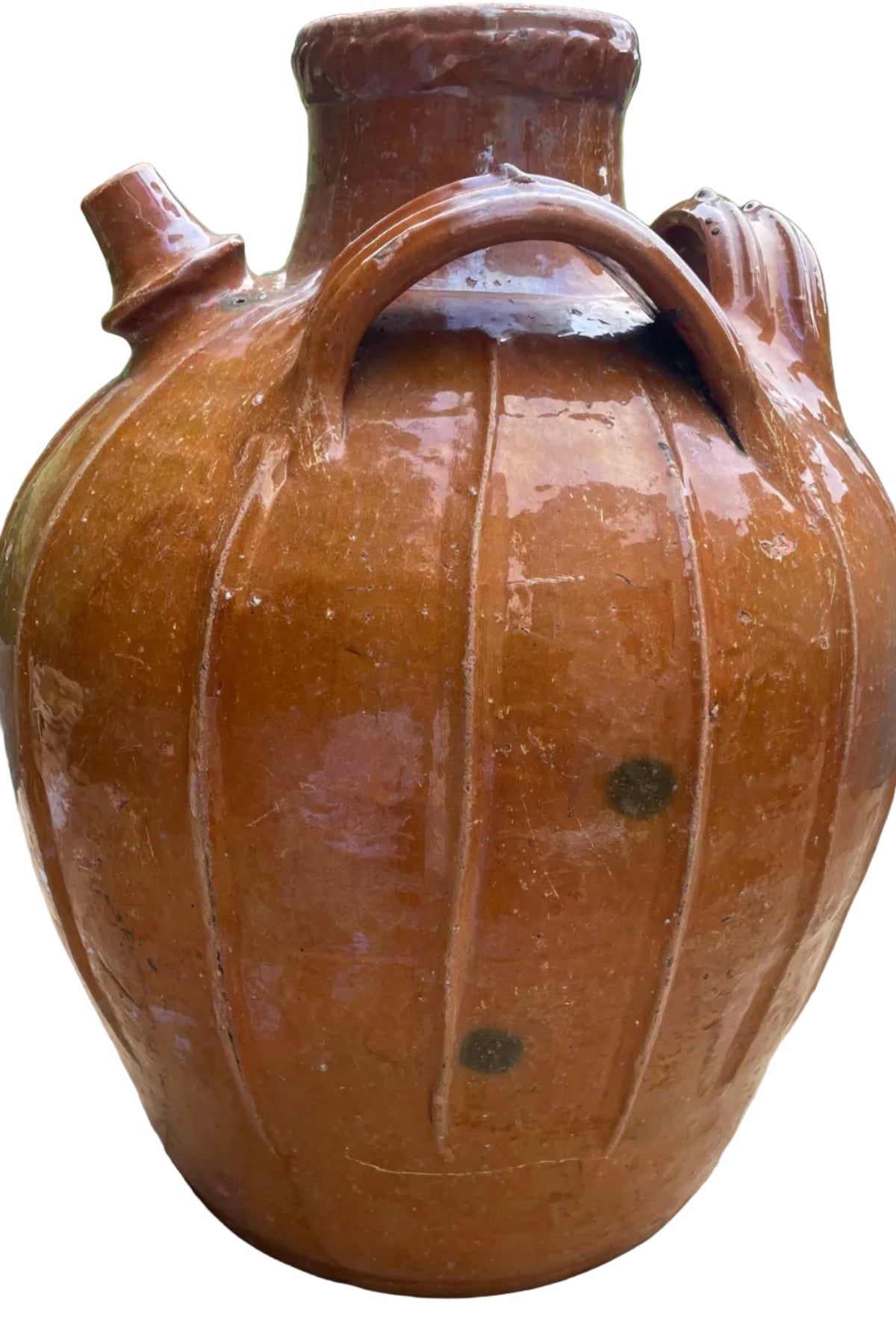 large rustic brown ceramic jug with a glossy finish, featuring a ribbed pumpkin-like body, a short neck, and a side spout, sitting on a wooden deck outdoors.
