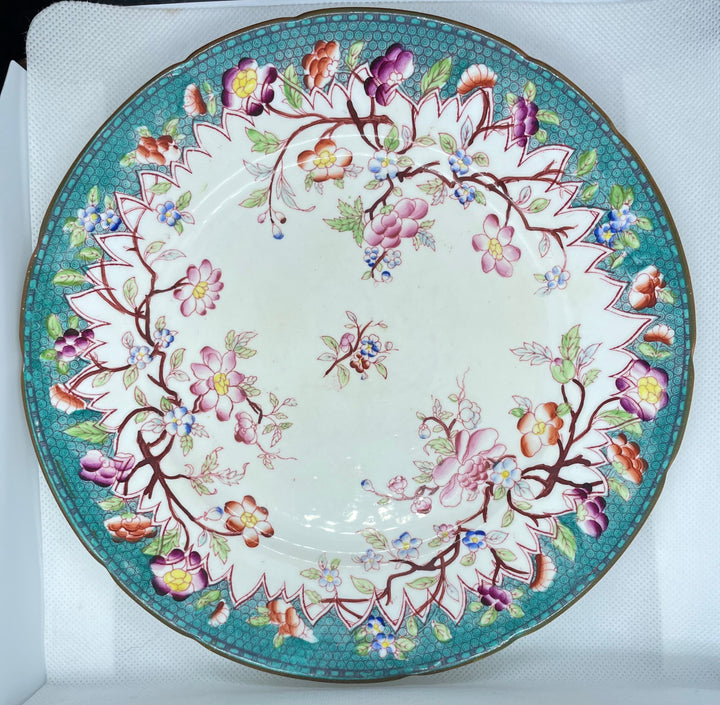 An oval ceramic plate with a white center, decorated with a vibrant turquoise border and delicate pink, purple, yellow, and green floral motifs.