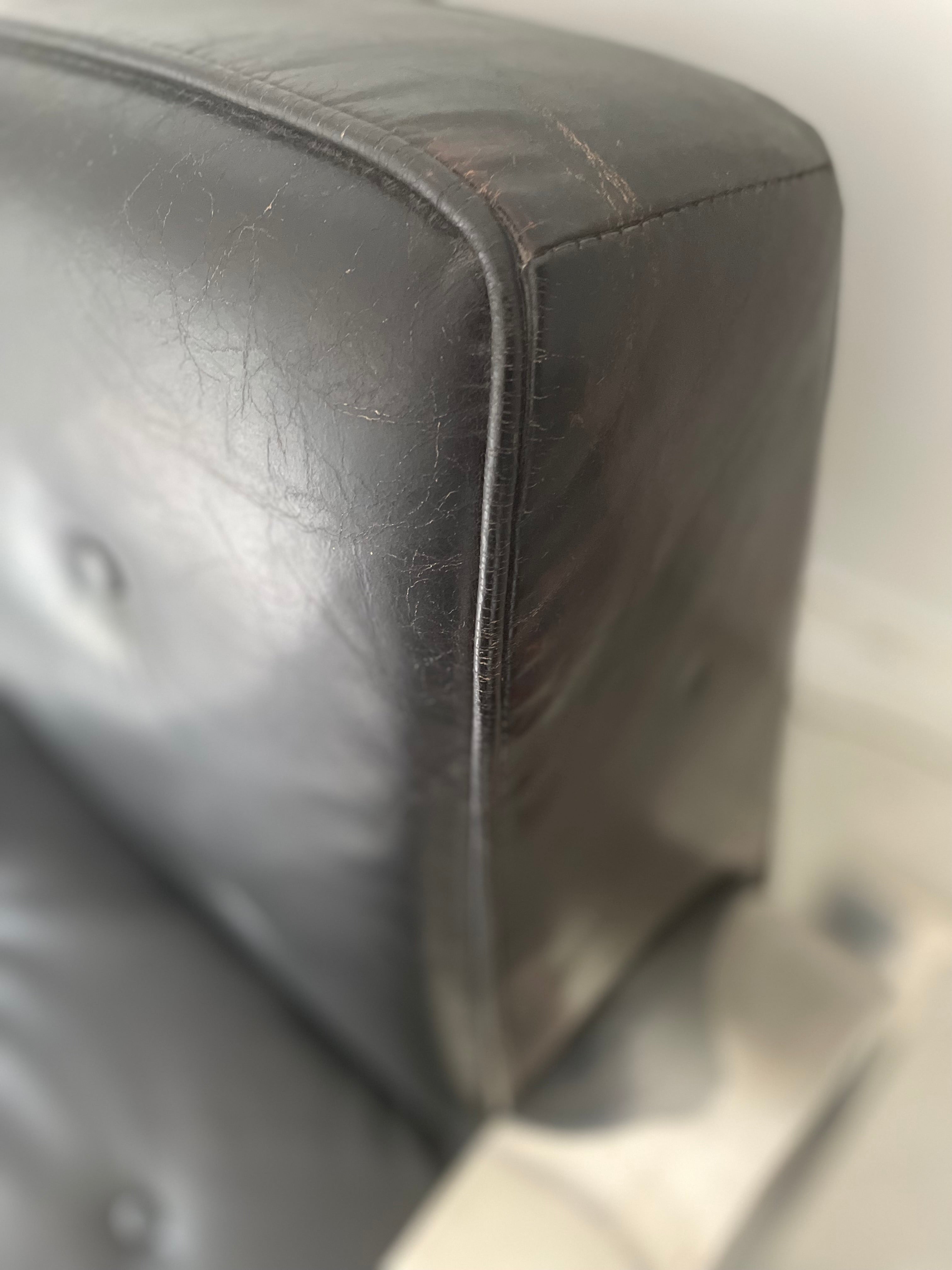 Close-up of a alvor aalto black leather armchair corner with visible wear.
