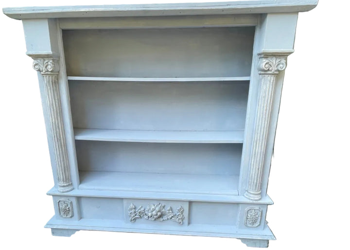 A light blue painted wooden bookcase with three shelves and decorative column details on the sides